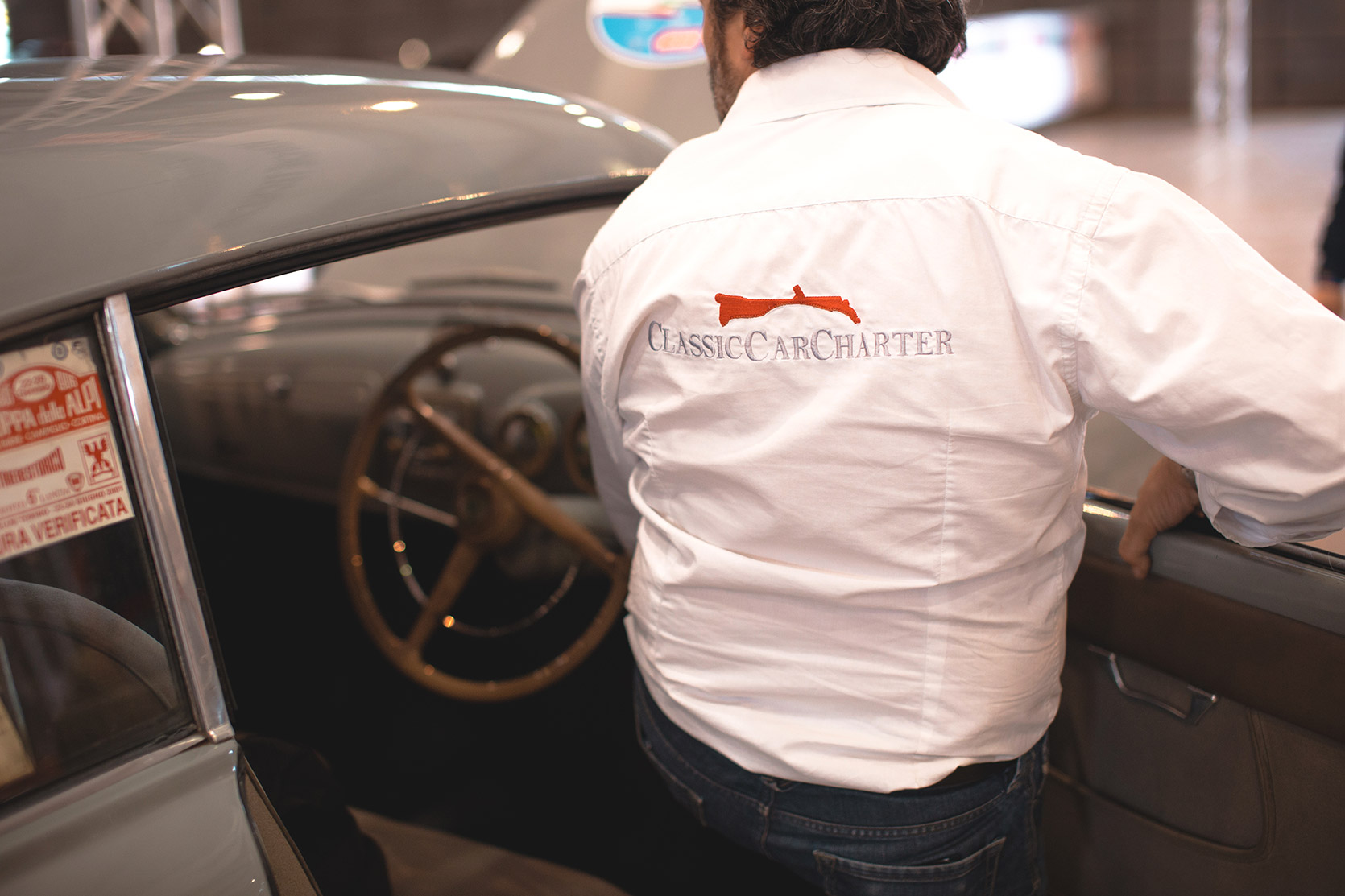 The owner of the Classic Car Charter pushing a Lancia Aurelia B20 from the door to the Mille Miglia checks