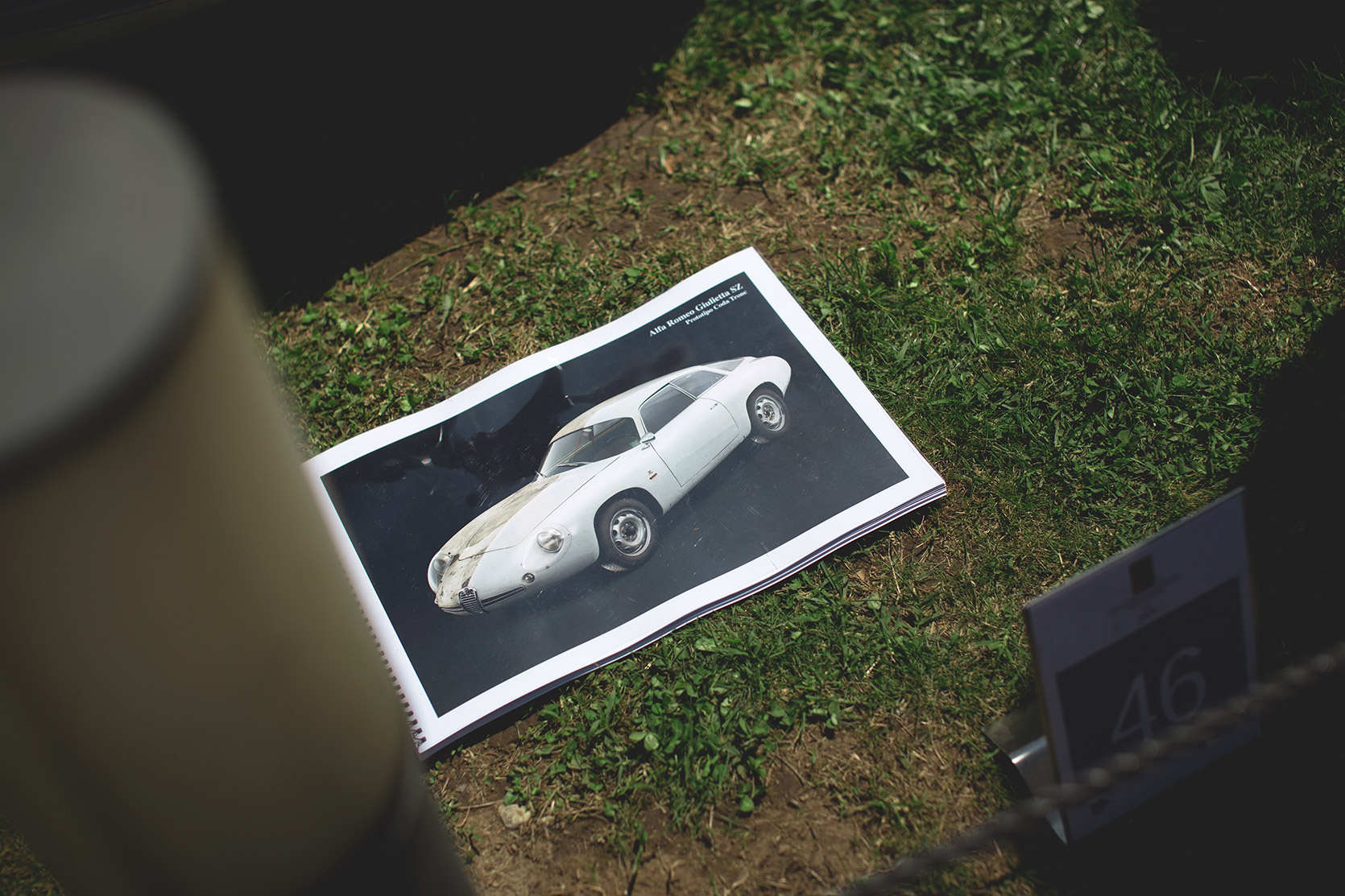 The work in progress book of the Lopresto's Alfa Romeo Giulietta SZ leaning on grass at Concorso d'Eleganza Villa d'Este