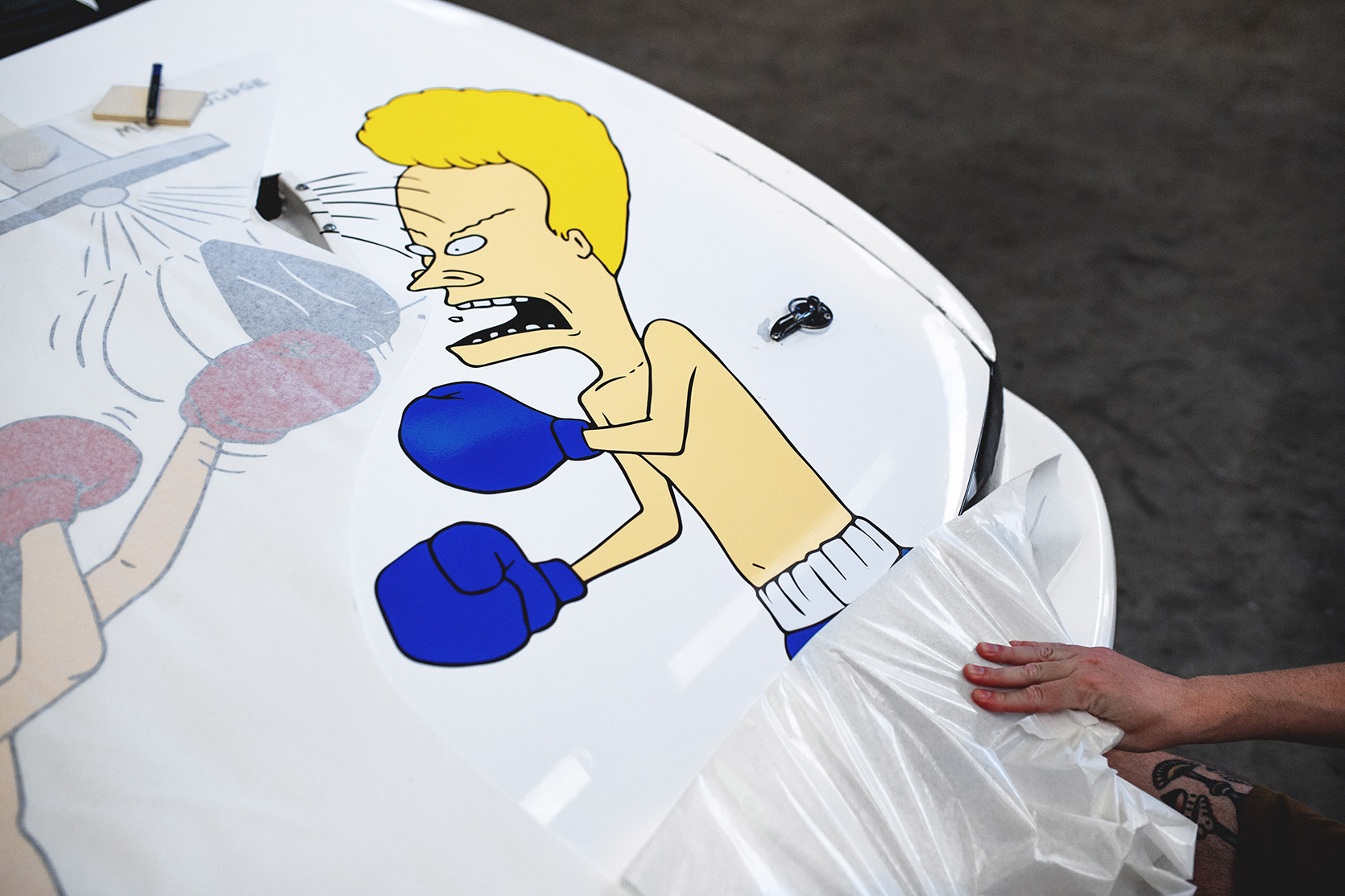 MH applying the Beavis and Butt-Head sticker by Iuter on Rizphel's Nissan Silvia S14 hood