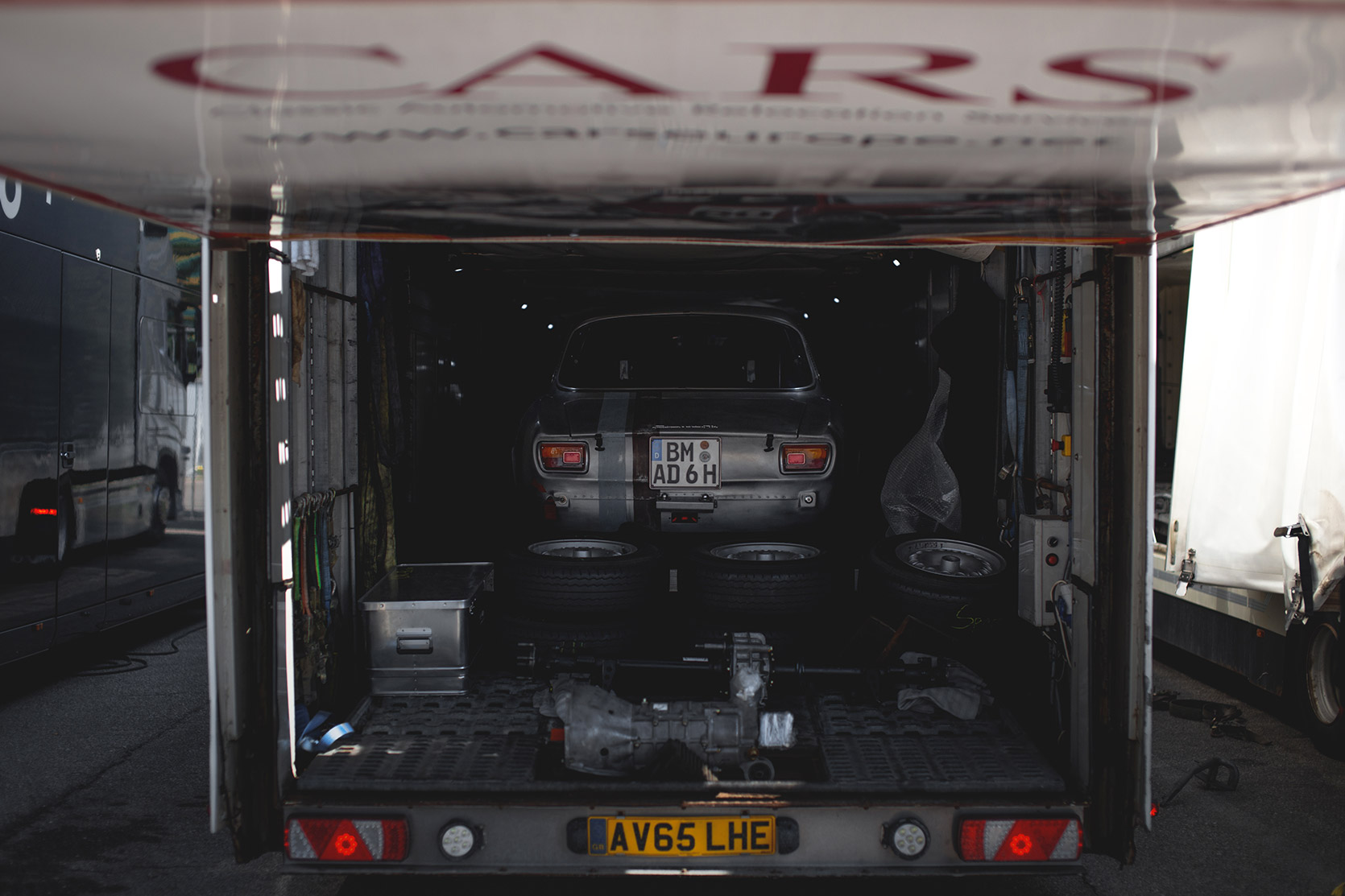 An Alfa Romeo Giulia Sprint in a truck ready to be unloaded in the paddock of Autodromo Nazionale Monza at Modena 100 Ore