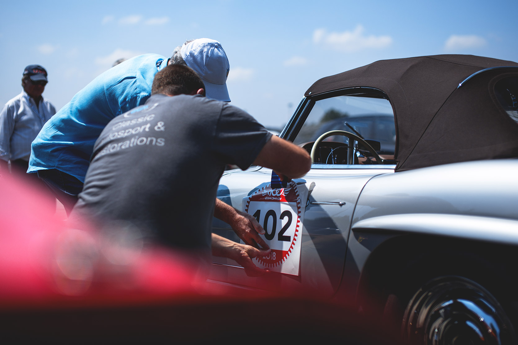 Participants applying number sticker on a door of a Mercedes 300SL in the paddock of Autodromo Nazionale Monza at Modena 100 Ore