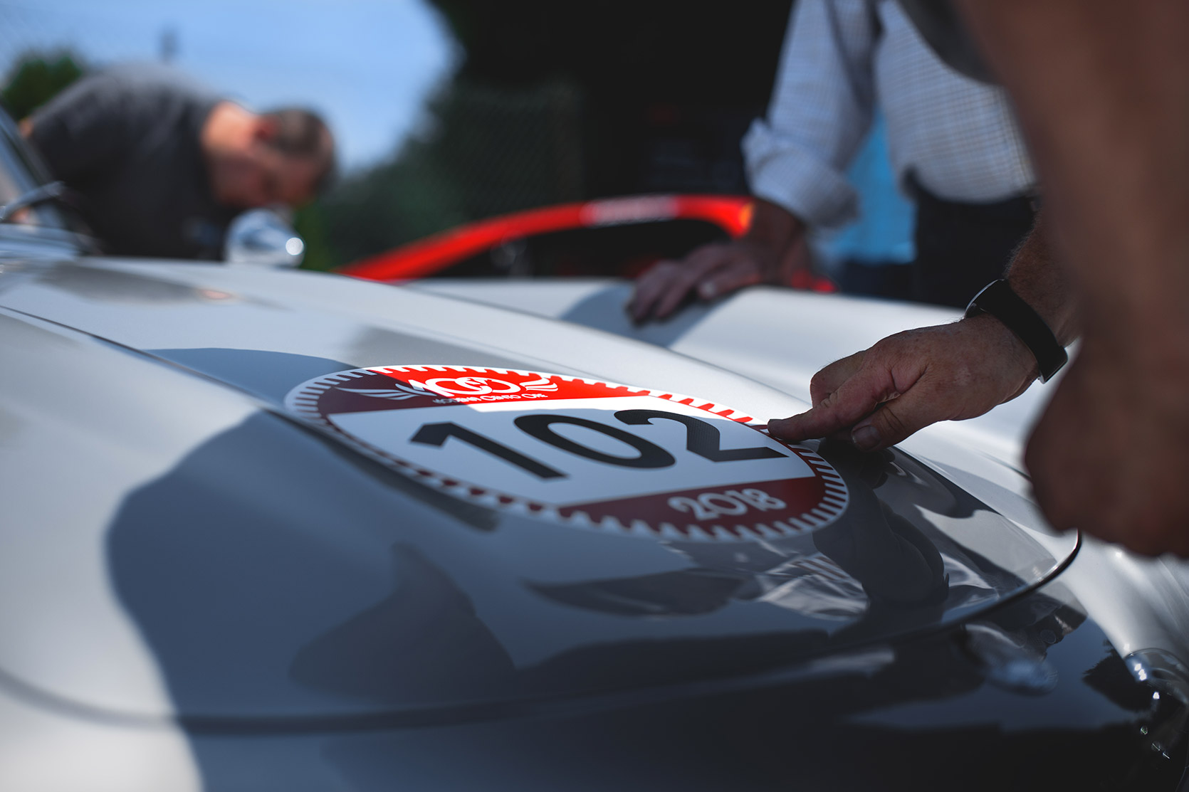 Participants applying number sticker on a hood of a Mercedes 300SL in the paddock of Autodromo Nazionale Monza at Modena 100 Ore