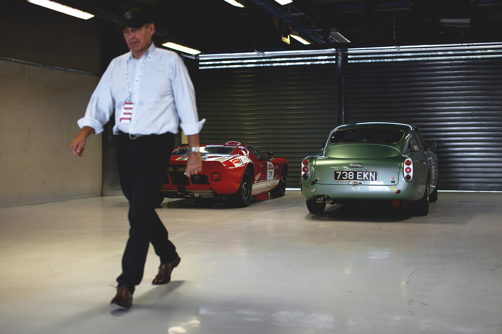 A Ford GT40 an Aston Martin DB4 and its owner moving away in the box of Autodromo Nazionale Monza at Modena 100 Ore