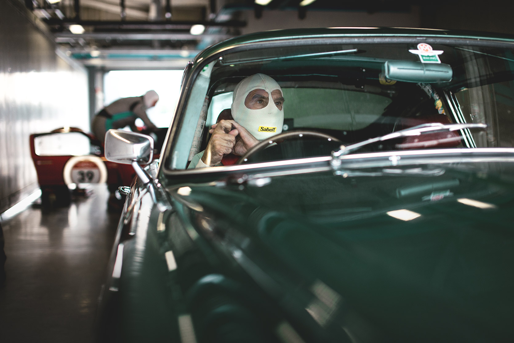 Driver preparing for the race in his Aston Martin DB4 in a box of Autodromo Nazionale Monza at Modena 100 Ore
