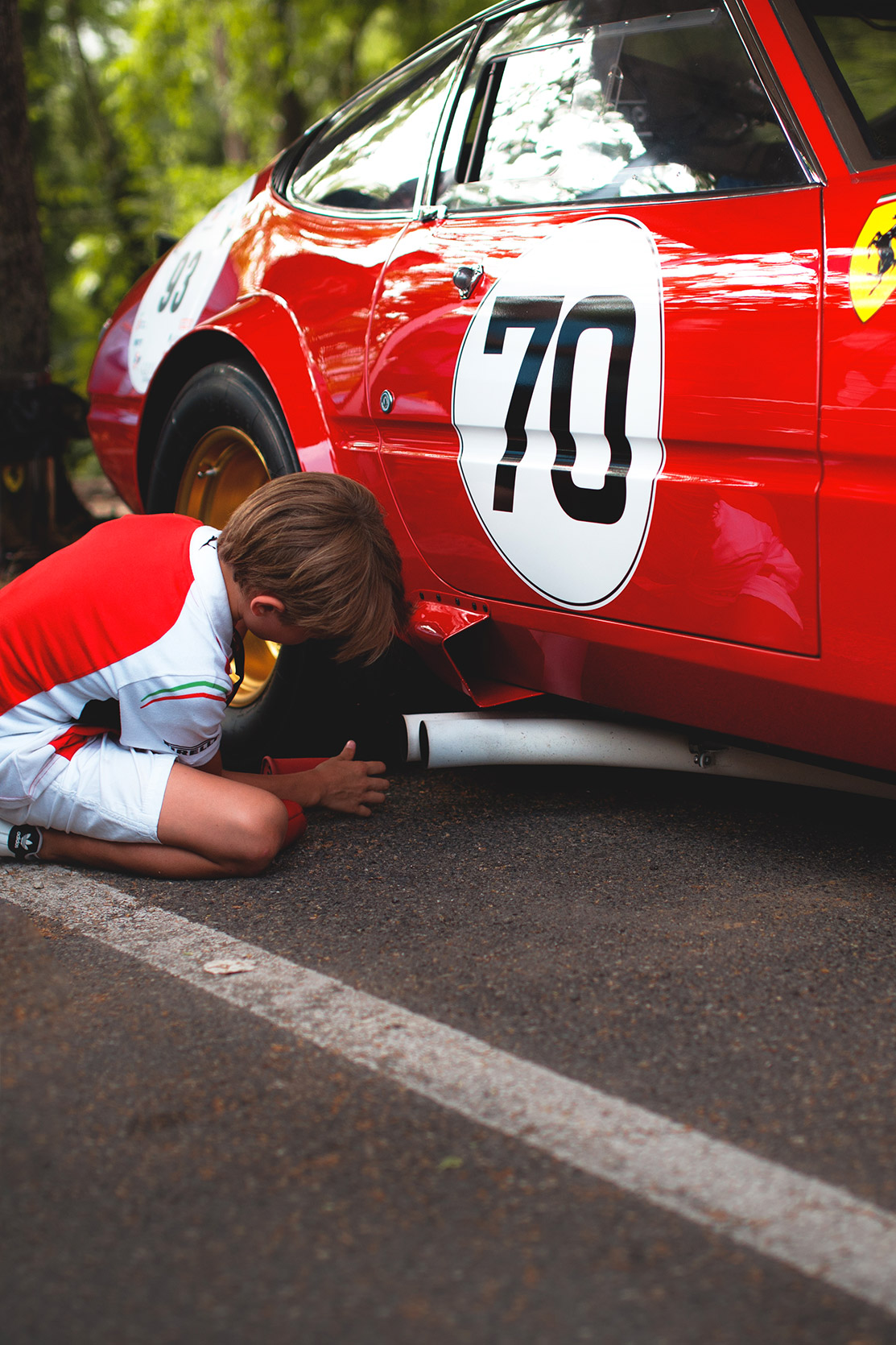 A kid is removing the exhaust cover of a Ferrari Daytona 365 GTB4 at Vernasca Silver Flag