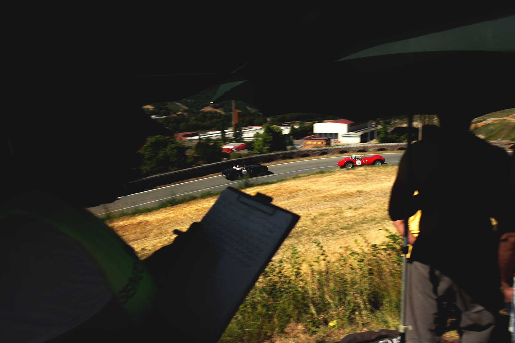 An Alfa Romeo 1900 Barchetta and a Maserati 250s passing while the Marshal is checking