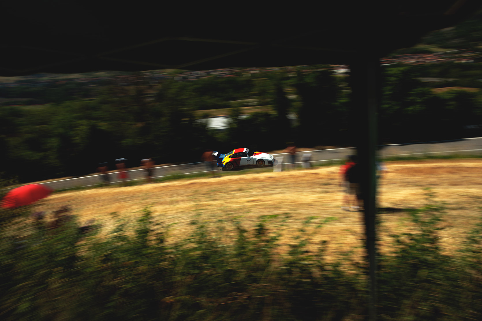 A panning of a Porsche 911 RSR Kremer climbing the hill at Vernasca Silver Flag